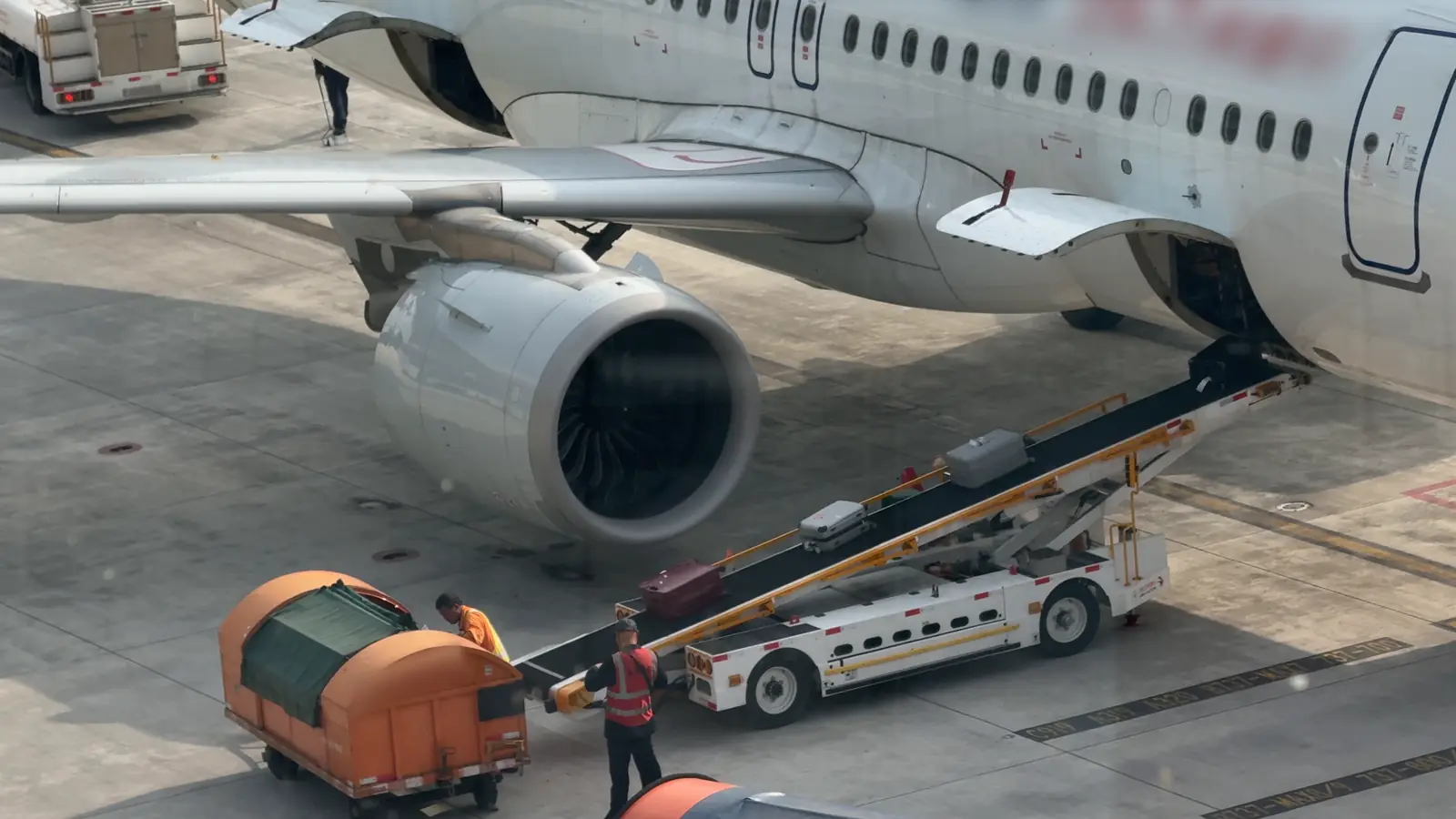 Ground handlers loading baggage with a belt loader